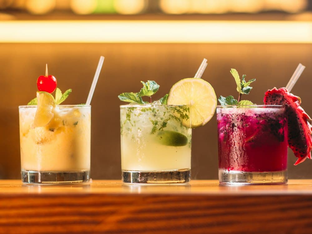Three colourful mocktails on a bar counter