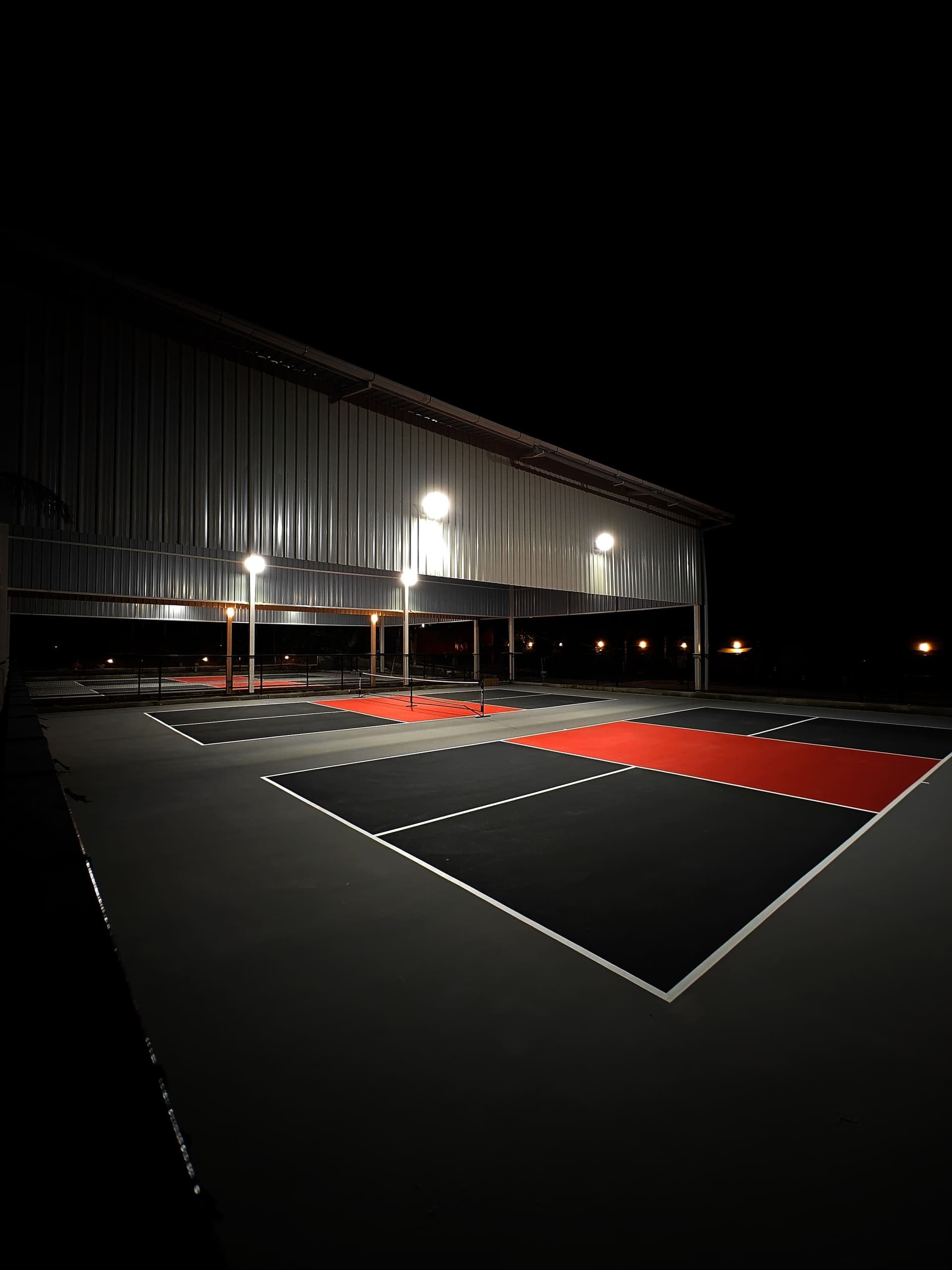 Dinklr's pickleball courts under floodlights at night
